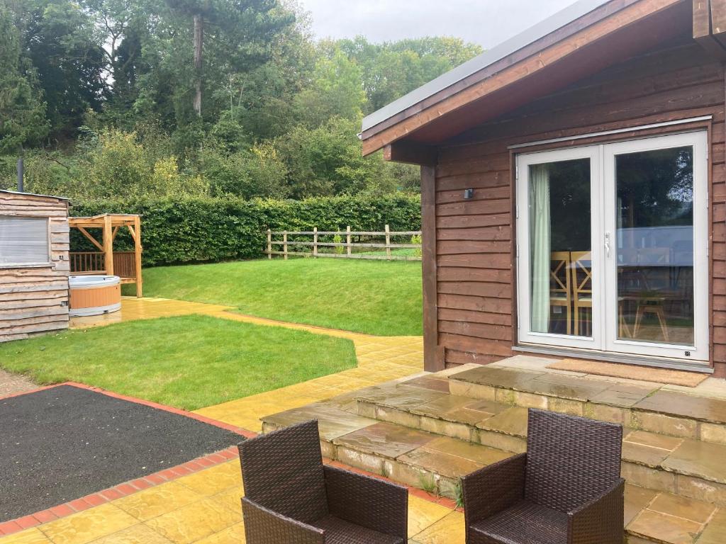 a garden with a patio with chairs and a lawn at Stag Lodge School House Farm in Leighton