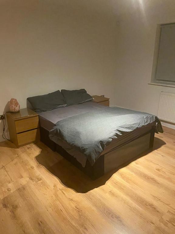 uma cama num quarto com piso em madeira em Birkbeck House em Beckenham