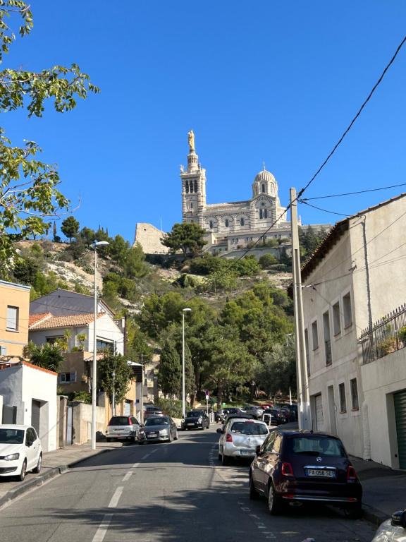 una calle con coches estacionados en una colina con un castillo en Douceur entre Notre Dame et la mer, en Marsella