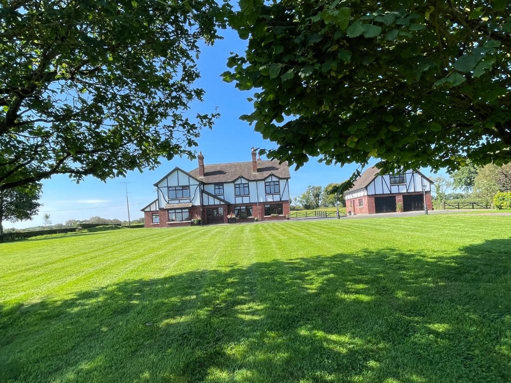 una casa grande con un gran campo de césped en Greenfields Country House, en Latton