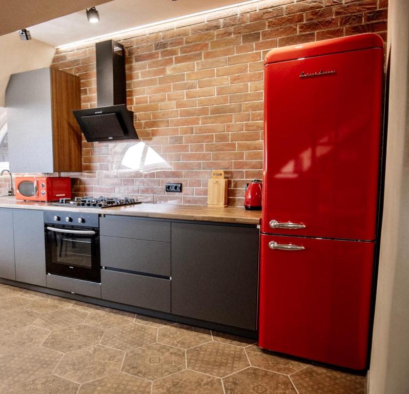 a red refrigerator in a kitchen with a brick wall at Стильна та затишна квартира ЦЕНТР, ЖД вокзал, Елітний будинок in Ternopilʼ