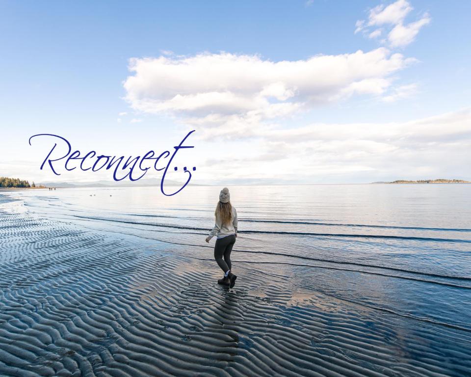 Una mujer caminando por la playa con las palabras reabiertas en Tigh-Na-Mara Seaside Spa Resort, en Parksville