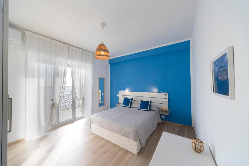 a blue bedroom with a bed and a blue wall at Majú Home in Maiori