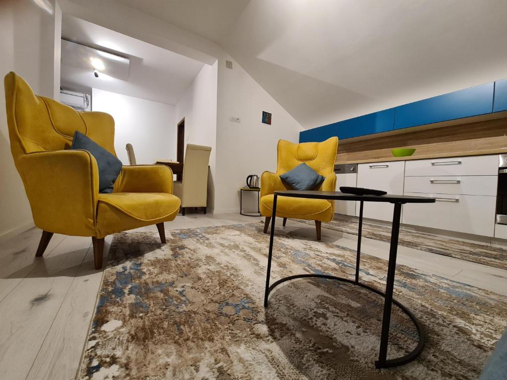 duas cadeiras amarelas e uma mesa numa sala de estar em Sovran's dream 2bedroom Apt 10min wak from center em Pristina