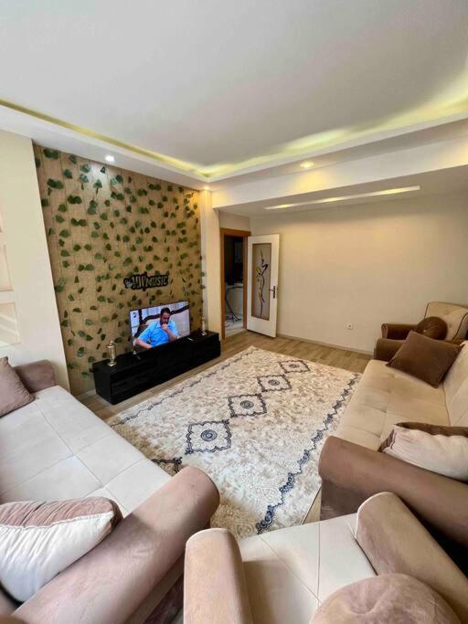 sala de estar con 2 sofás y TV de pantalla plana en Şirinevler Büyük Daire, en Estambul