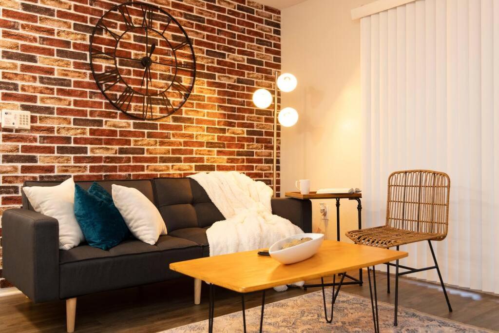 a living room with a couch and a brick wall at Stylish Serenity: Your Central Peace Zone! in Gainesville