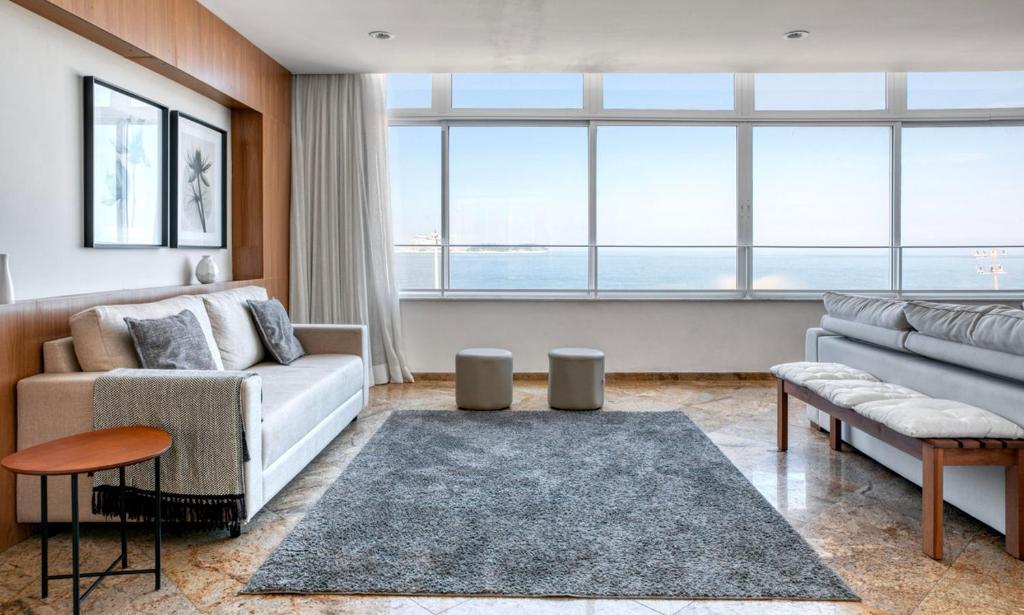 uma sala de estar com um sofá e uma grande janela em Tabas Lindo em frente a Praia de Ipanema IP0007 no Rio de Janeiro