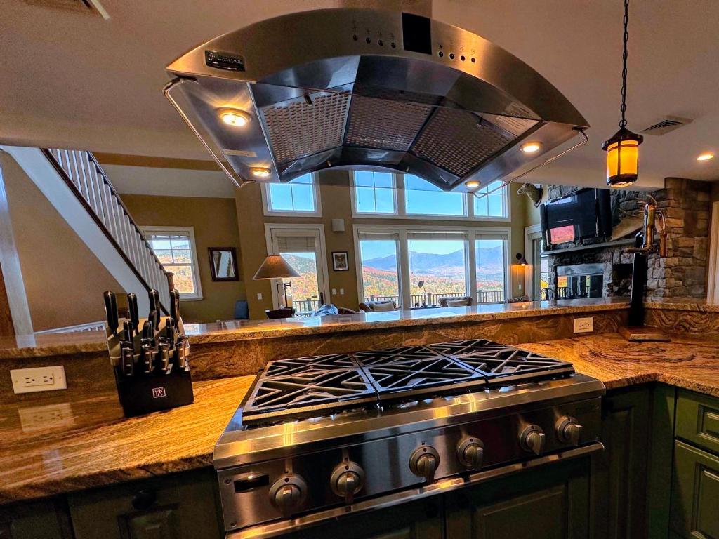 a kitchen with a stove and a large hood at Presidential View Ski-in Ski-out Townhome with Amazing Views in Bretton Woods