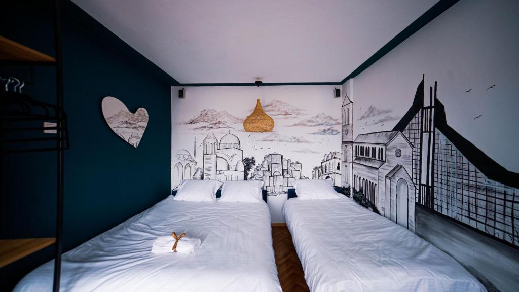 sypialnia z dwoma łóżkami i rysunkiem na ścianie w obiekcie Prishtina In & Out w Prisztinie