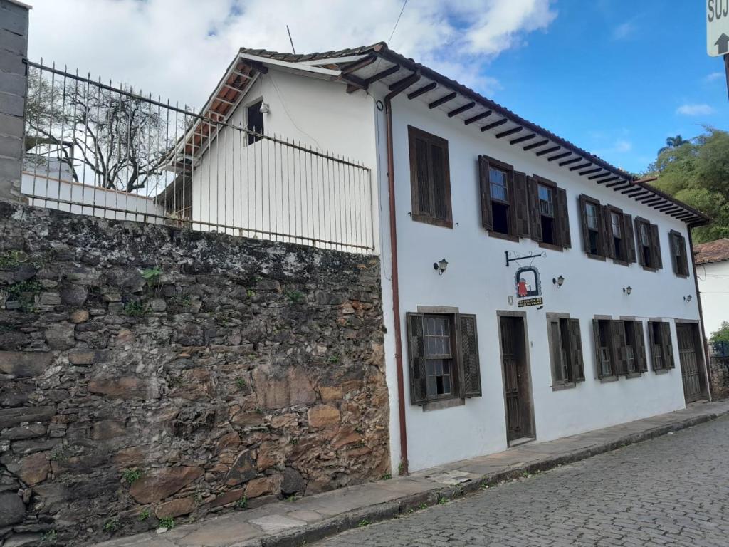 a white building next to a stone wall at Republica Do Arco Da Velha in Ouro Preto