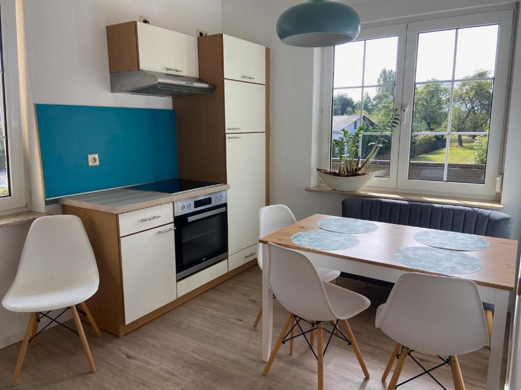 cocina con mesa de madera y sillas blancas en Seeblick Apartments Mühlau, en Mühlau