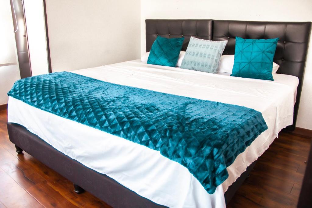 ein Bett mit einer blau-weißen Decke drauf in der Unterkunft apt duplex embajada americana corferias agora g12 in Bogotá