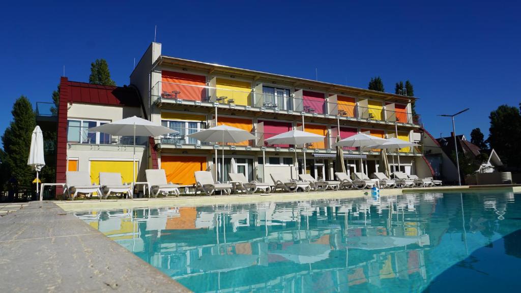 um hotel com uma piscina com cadeiras e guarda-sóis em Colors Holiday Hotel em Siófok