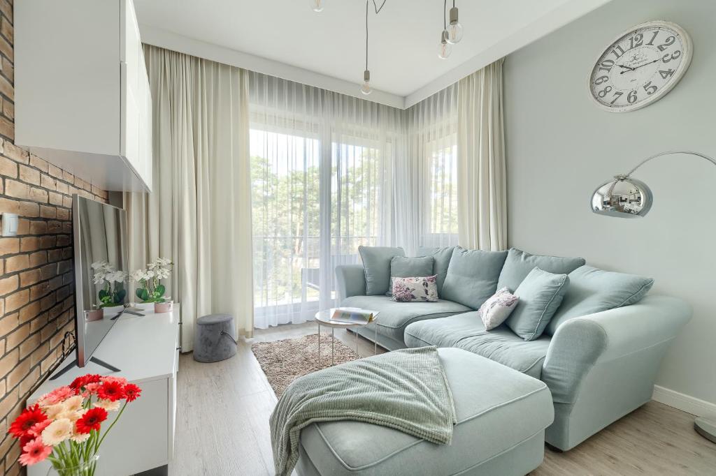 a living room with a couch and a clock on the wall at Apartament Doris 1 z pięknym widokiem in Pobierowo