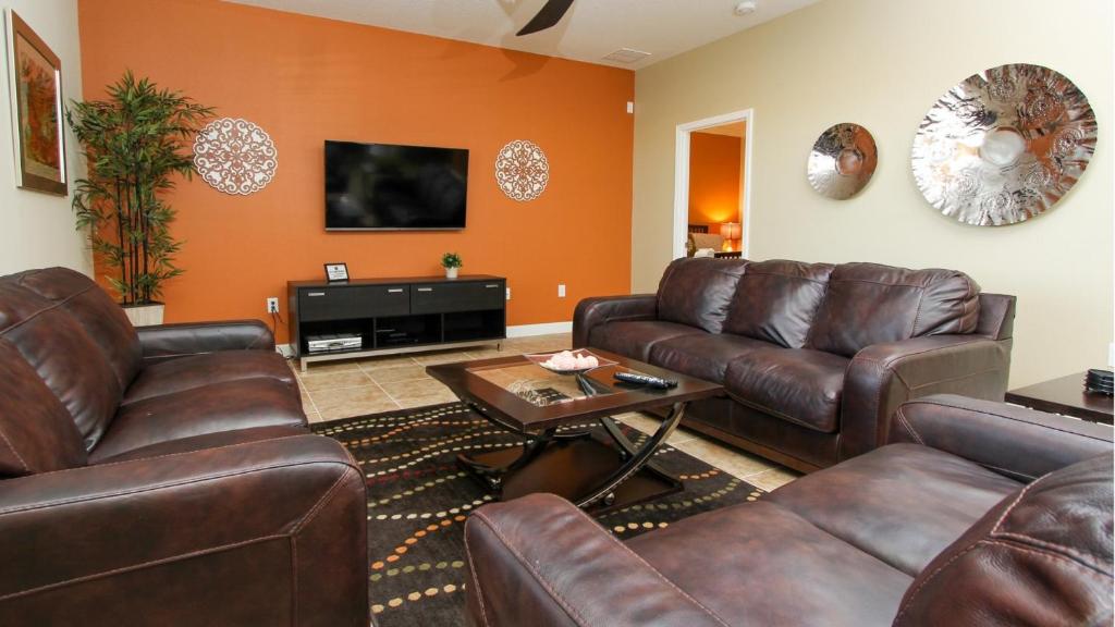 una sala de estar con sofás de cuero marrón y una mesa. en Champions Gate Resort - 5b4b Villa, en Davenport