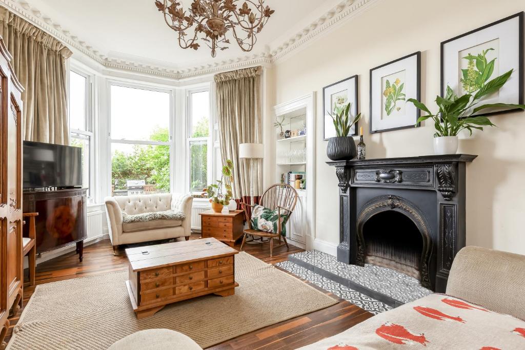 een woonkamer met een open haard en een televisie bij Stylish Victorian Apartment's close to the Botanical gardens, Free parking! in Edinburgh