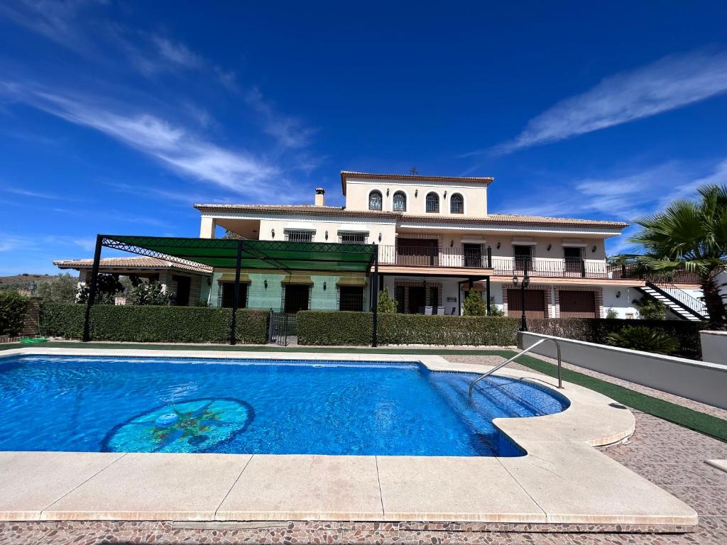 uma casa com piscina em frente a uma casa em Casa Rural El Mirador de la Atalaya em Villanueva de Algaidas