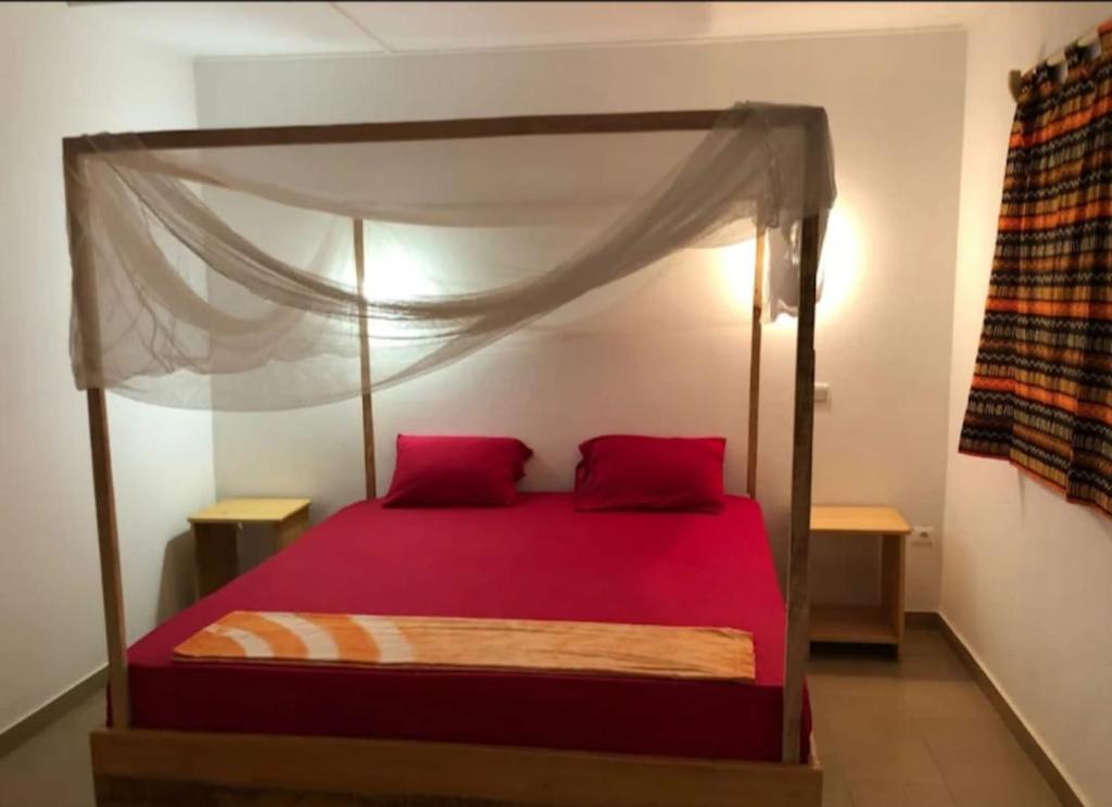 um quarto com uma cama de dossel e 2 almofadas vermelhas em CAMPAMENTO CHEZ CAMPOS em Cap Skirring