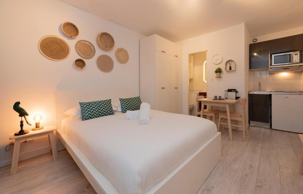une chambre avec un grand lit blanc et une cuisine dans l'établissement Le Roseau Toulousain, à Toulouse