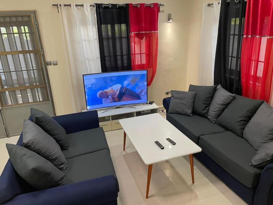 uma sala de estar com um sofá e uma televisão em Villa toute équipée à Arconville em Abomey-Calavi