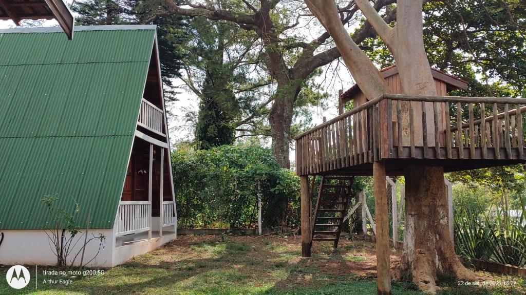 a tree house with a green roof and a staircase at Chalé Europeu na Beira do Rio in Pederneiras