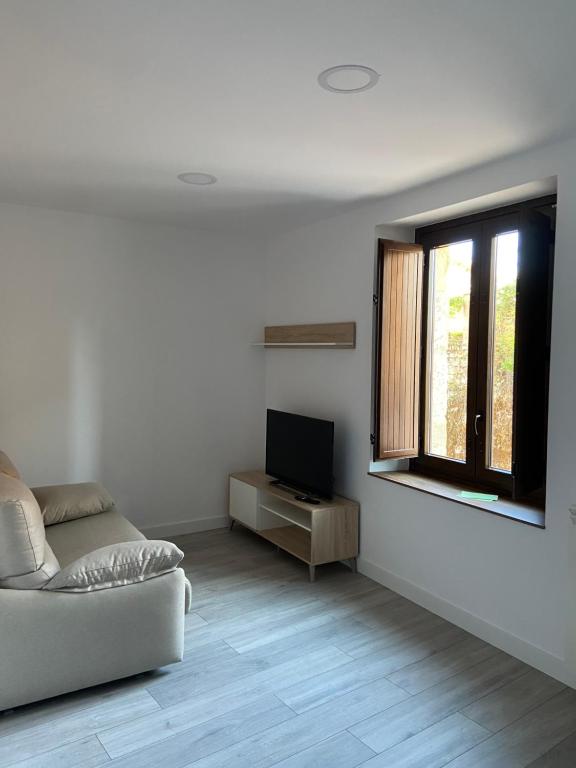 a white living room with a couch and a television at Apartamentos Rurales La Plaza 1 in Duruelo de la Sierra