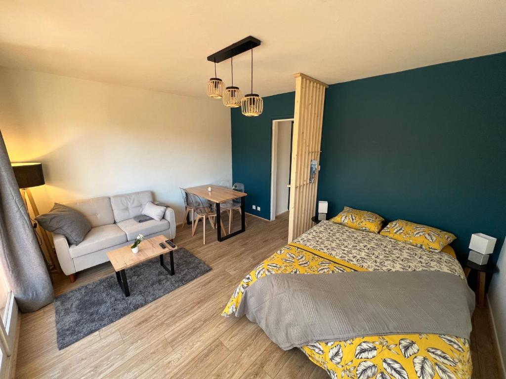 een slaapkamer met een bed en een bank bij Studio - La parenthèse Valognaise in Valognes