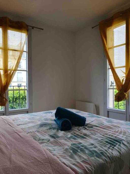 a bedroom with a large bed with two windows at Appartement Disney Paris in Serris