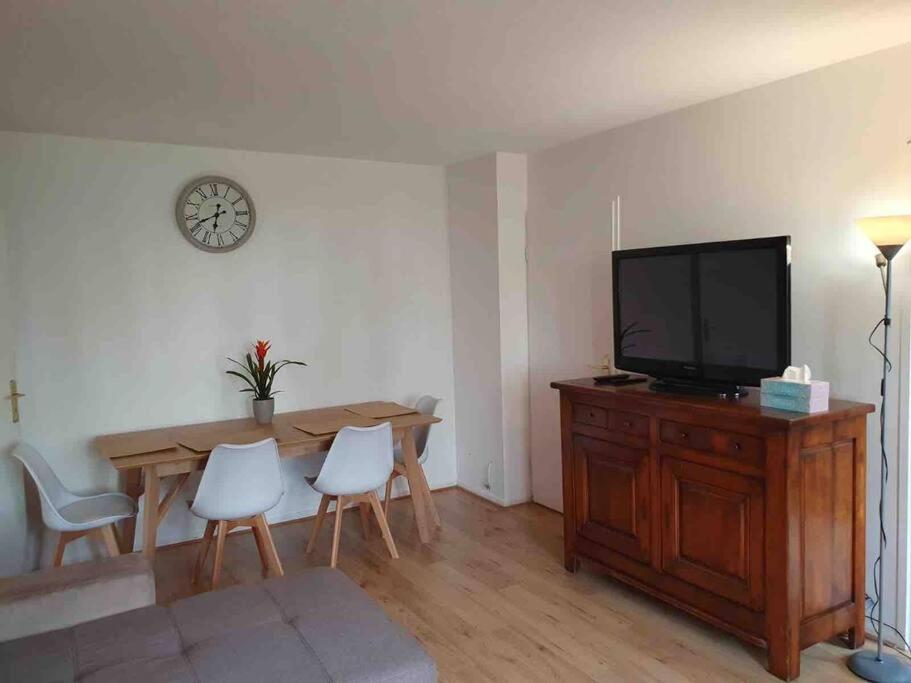 a living room with a television and a table and chairs at Appartement Disney Paris in Serris