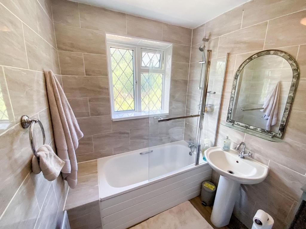 a bathroom with a sink and a bath tub and a mirror at Stunning Modern Cozy 5 star 3 bedroom house-Free Parking Greater London Metro Stations hosted by Tony in Catford