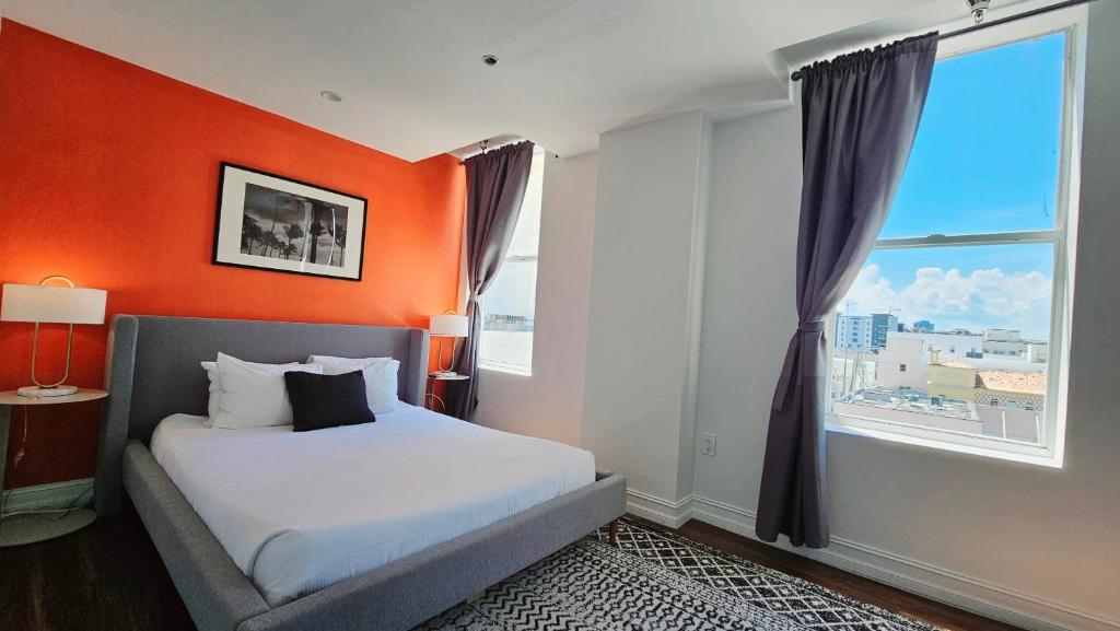 um quarto com uma parede laranja, uma cama e uma janela. em The Lofts on Clematis 407 Downtown West Palm Beach em West Palm Beach