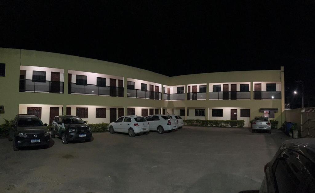 a large building with cars parked in a parking lot at Pousada Canaã in São Francisco de Itabapoana