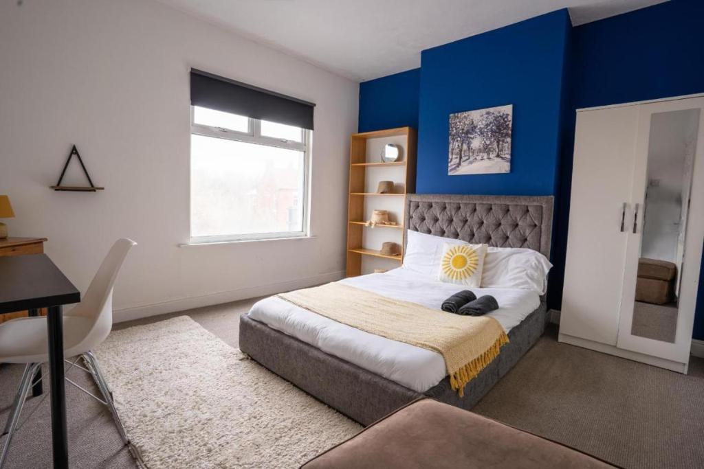 a bedroom with blue walls and a bed and a desk at Cozy 4-Bedroom in Coventry: Your Home Away From Home in Coventry