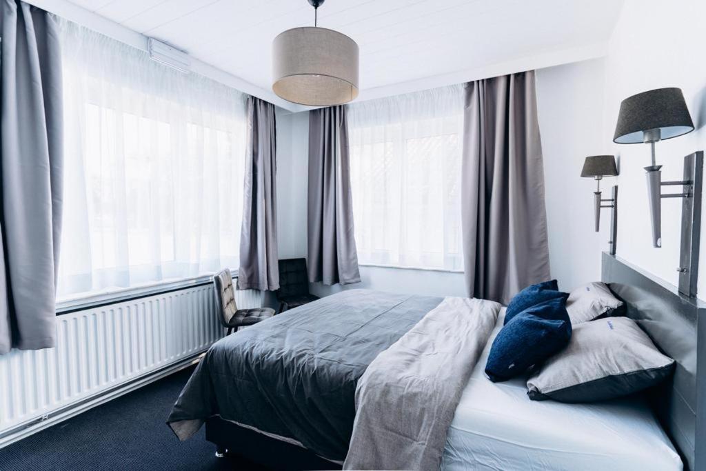 um quarto com uma cama com almofadas azuis e janelas em Atomihotel: Contemporary Comfort Steps from the Atomium! em Bruxelas