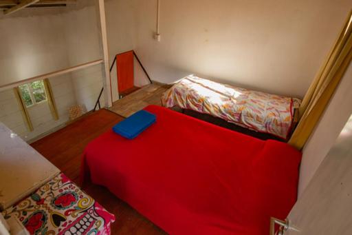 Habitación pequeña con cama roja y sofá en El descanso en Villa Carlos Paz