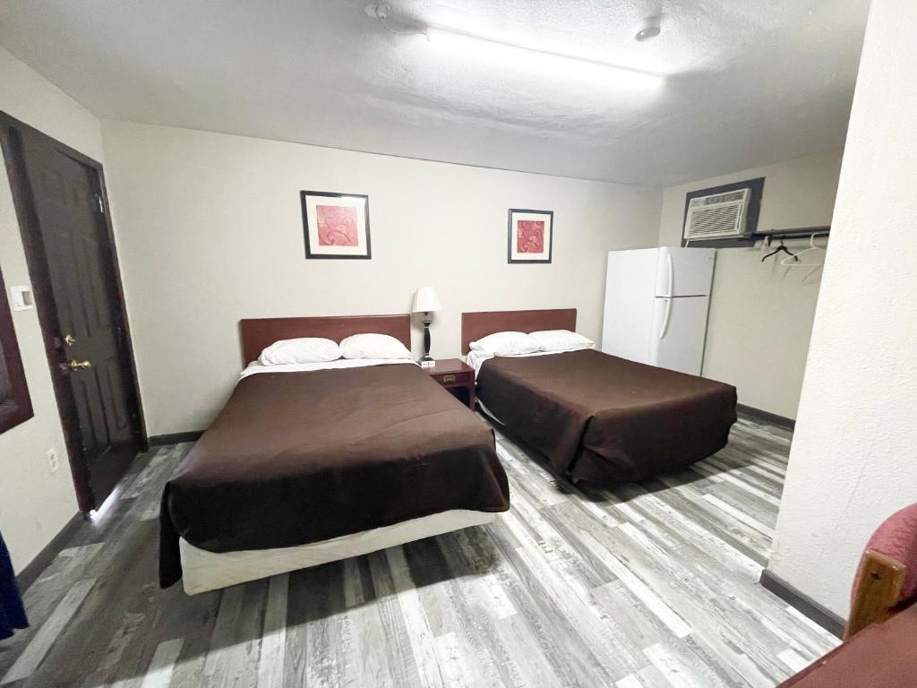 a hotel room with two beds and a refrigerator at Azure Sky Motel in Fort Scott