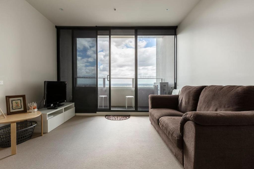 uma sala de estar com um sofá e uma grande janela em Light, Elevated Living near Queen Victoria Market em Melbourne