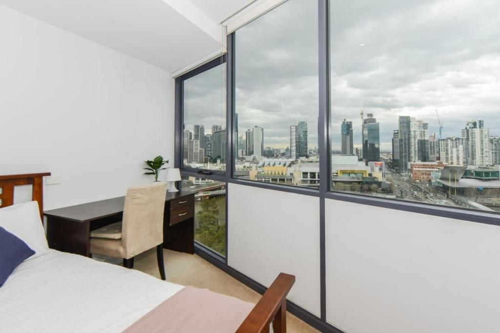 1 dormitorio con 1 cama, escritorio y ventanas en Backpackers' Delight with Sprawling City Views en Melbourne