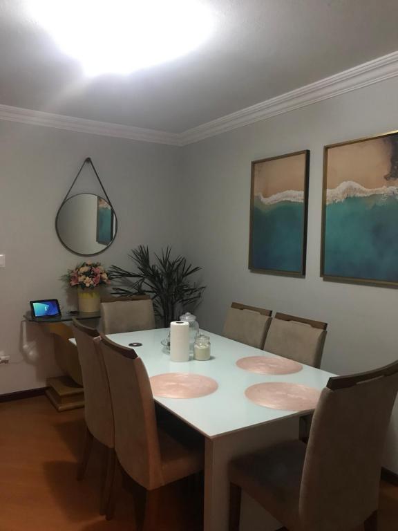 a dining room with a white table and chairs at Quarto para Casal Blumenau in Blumenau