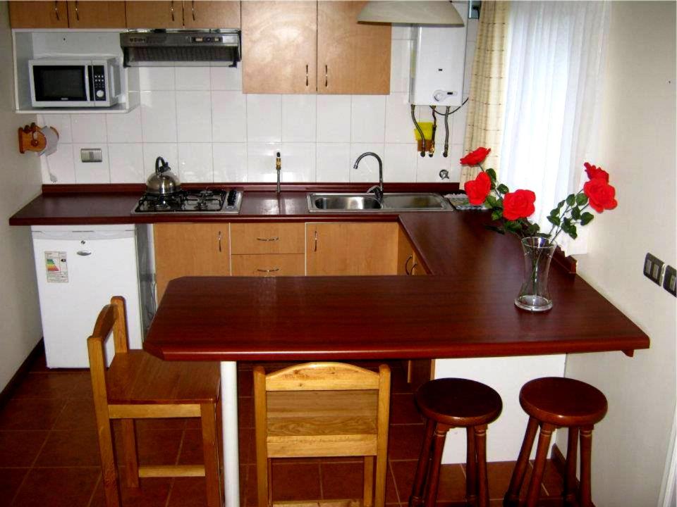 a kitchen with a wooden counter with chairs and a sink at Cabañas CentroMontt in Puerto Montt