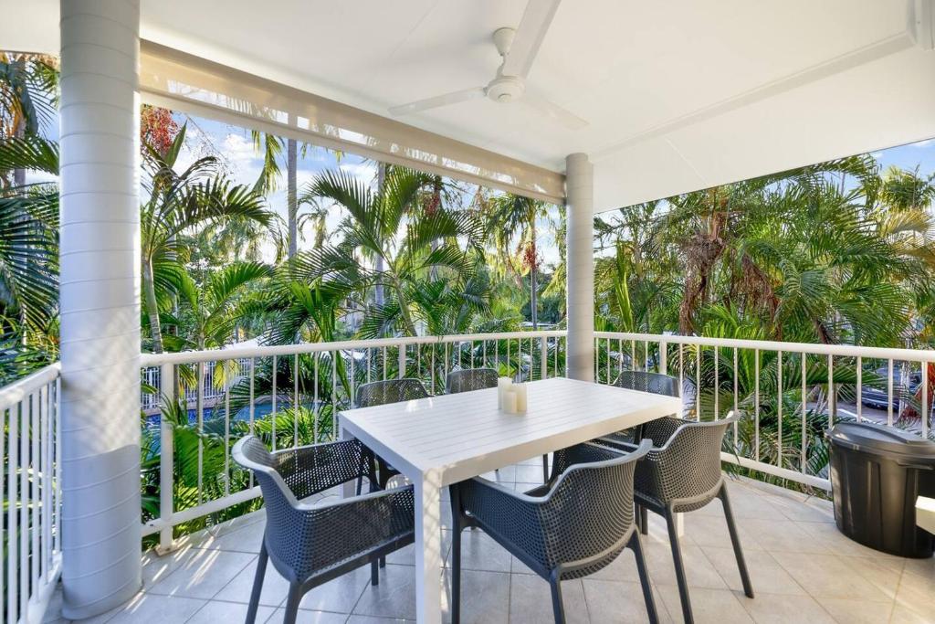 a table and chairs on a balcony with palm trees at Discover a Scandi Style Pool Retreat in Nightcliff in Darwin
