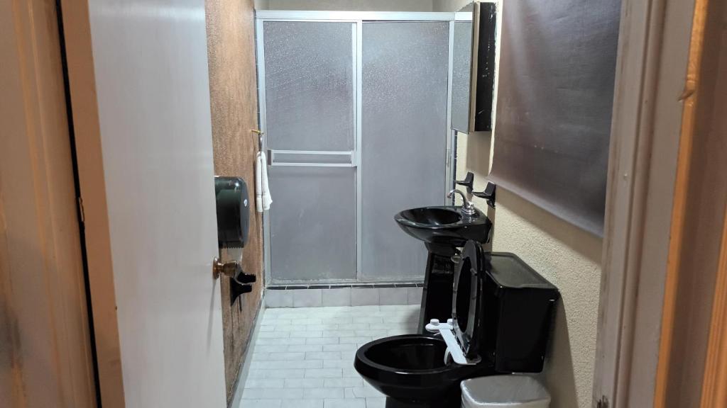 a bathroom with a black toilet and a glass door at Fitness Suite in Tijuana