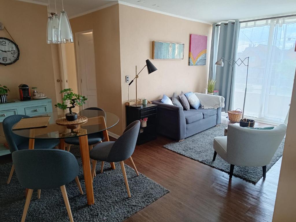 een woonkamer met een tafel en stoelen en een bank bij Cómodo departamento en Curicó in Curicó