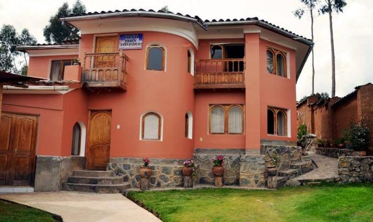 Una gran casa naranja con balcón. en Casa Tejedora en Chincheros