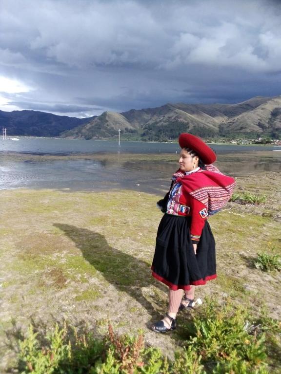 Una ragazza in piedi in un campo vicino all'acqua di Casa Tejedora a Chincheros