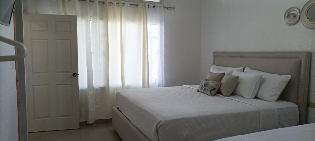 Habitación blanca con cama y ventana en Apartamentos Manik, en Trujillo