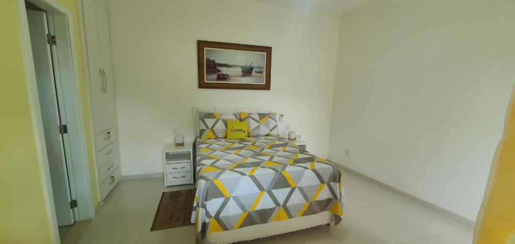 a bedroom with a bed with a yellow and white bedspread at Pousada da Drica in Saquarema