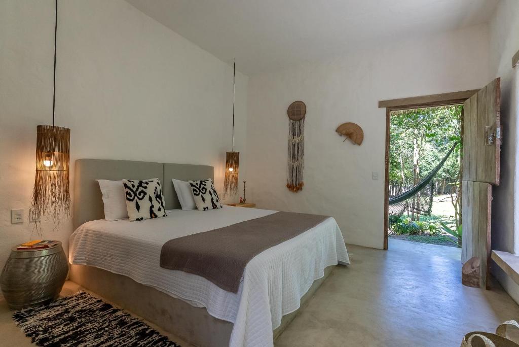 een slaapkamer met een groot bed en een glazen schuifdeur bij Suítes Casa Kamayurá in Trancoso