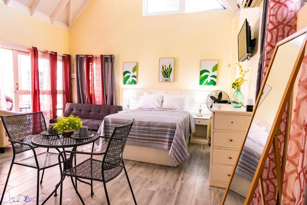 1 dormitorio con 1 cama, mesa y sillas en Sunsets at Sunshine Village Lofts, en Negril