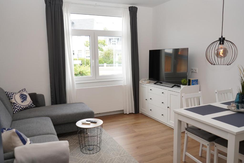 ein Wohnzimmer mit einem Sofa und einem TV in der Unterkunft Strandhaus Döse 1 in Cuxhaven